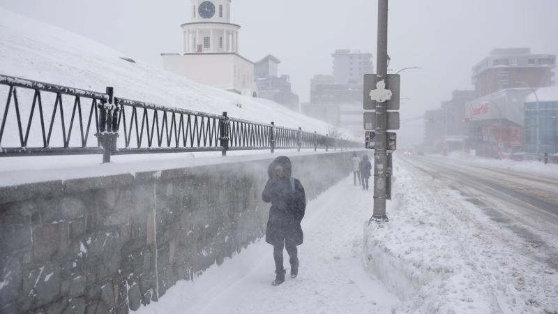 Pedestrians make their way through blowing snow as a winter storm continues to batter Halifax on Sunday, Feb. 4, 2024. Environment Canada has maintained weather alerts across Nova Scotia with predictions anywhere from 30 to 100 centimetres of snow in parts of the province. THE CANADIAN PRESS/Darren Calabrese