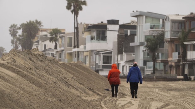 People walk next to a sand berm built by the city of Long Beach in preparation for high tide along the Peninsula in Long Beach, Calif., Monday, Feb. 19, 2024.<br><br>
The latest in a series of wet winter storms gained strength in California early Monday, with forecasters warning of possible flooding, hail, strong winds and even brief tornadoes as the system moves south over the next few days.<br><br>
(AP Photo / Damian Dovarganes)