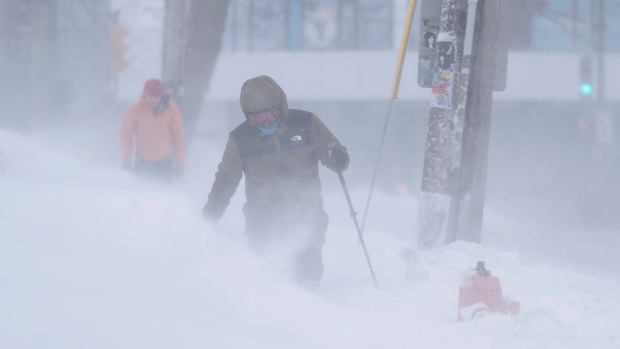 Pedestrians make their way through drifting snow as heavy snow and gusting winds continue to hit Halifax on Sunday, Feb. 4, 2024. THE CANADIAN PRESS/Darren Calabrese