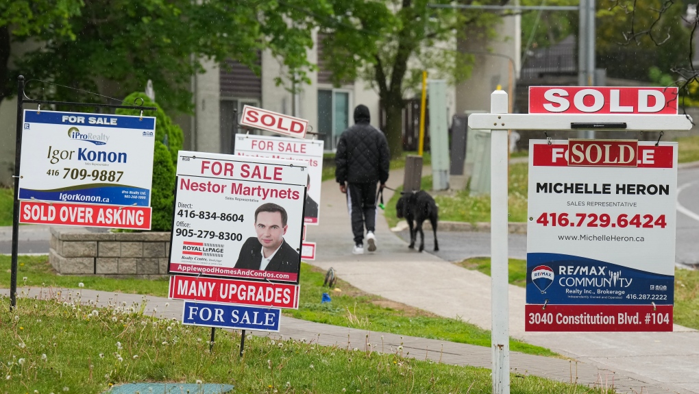 A person walks past multiple for sale and sold real estate signs in Mississauga, Ont., on Wednesday, May 24, 2023. (THE CANADIAN PRESS/Nathan Denette)