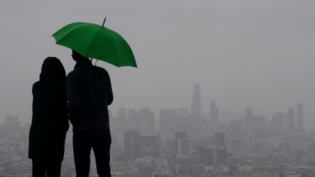 FILE: People stand under an umbrella while looking toward the skyline from Twin Peaks in San Francisco. (AP Photo/Jeff Chiu)