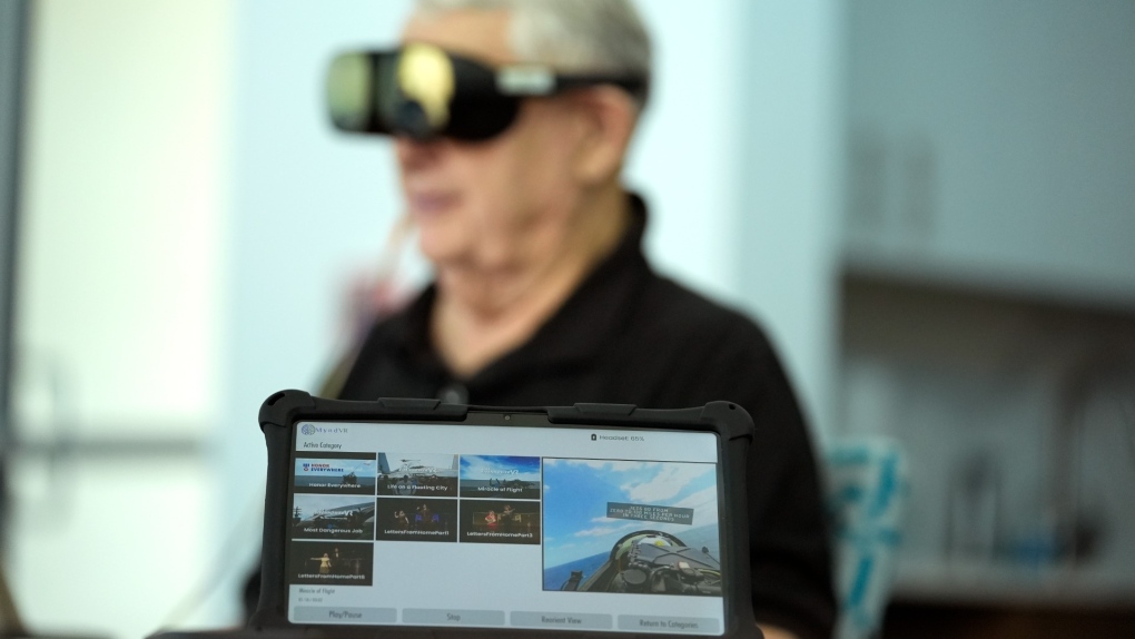 A screen displays a visual of being in a navy fighter jet as retired U.S. army colonel Farrell Patrick, 91, wears a Mynd Immersive virtual reality headset at John Knox Village, Jan. 31, 2024, in Pompano Beach, Fla. (AP Photo/Lynne Sladky)